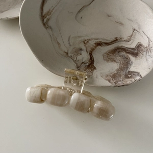 Detail of elegant amber marble pattern hair claw clip with transparent inner teeth
