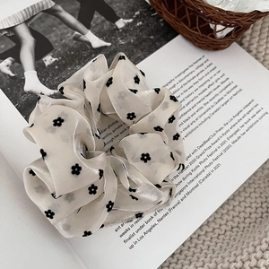 Detailtextur von cremefarbenem Mesh-Lace-Haargummi mit schwarzen Blumenmustern auf Buch