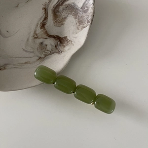 Close-up of elegant olive green rectangle resin beads on a golden hair clip base