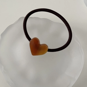 Detail of amber acetate heart pendant on a black elastic hair tie for women