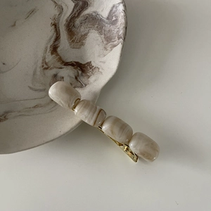 Detailed close-up of amber texture marble beads on a gold-plated metal hair clip