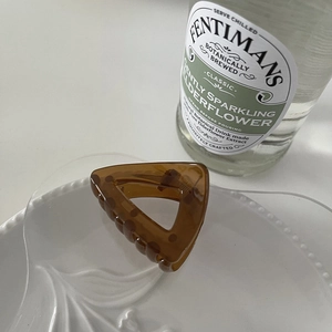 Detail view of a translucent amber triangular hair claw clip on a white ceramic plate