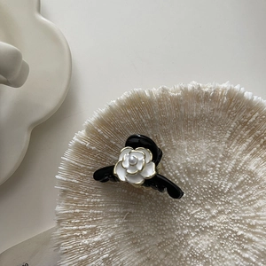 Detail of elegant black hair claw clip featuring a white camellia flower with pearl center