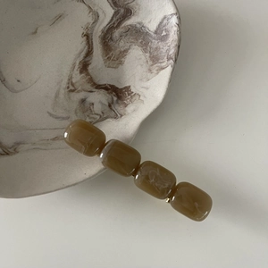 Detailed macro view of four amber marble resin beads on a minimalist hair clip design
