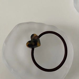 Detailed close-up of a tortoise shell acetate heart hair tie on a frosted tray