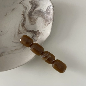 Detailed view of elegant amber marble beads hair clip on minimalist ceramic tray