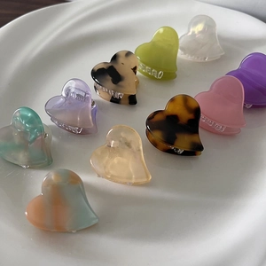 Mini heart acetate hair claws set with colorful marble patterns in a ceramic dish