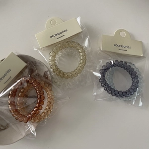 Dettaglio degli elastici a spirale per capelli in toni Morandi con confezione in cartone