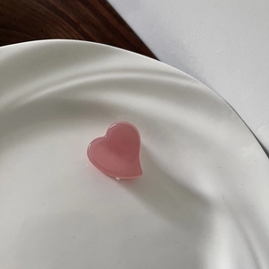 Pink heart-shaped mini hair claw clip made of acetic acid resin on white ceramic plate