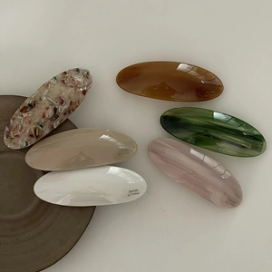 Vue détaillée de six barrettes en acétate brillant aux motifs ambre, crème et écaille de tortue