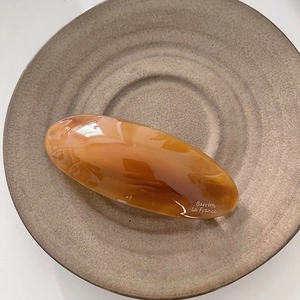 Détail de la barrette ambrée avec logo Barrette la France sur un plateau en céramique