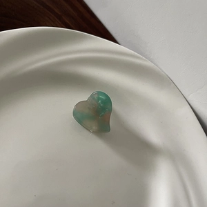 Macro detail of a heart-shaped acetate mini hair claw clip with green marble texture