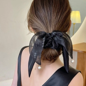 Detail of a vintage black bow hair scrunchie with silk ribbons and pearl pendants
