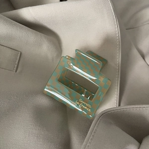 Detail view of acetate checkered hair claw in green and cream with golden lettering