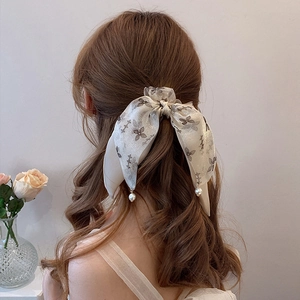 Elegant floral bow hair scrunchie with pearl pendants on wavy brown hair