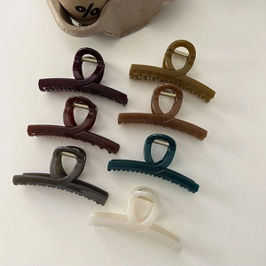Close-up of seven assorted colorful glossy acrylic claw clips in earth-toned shades