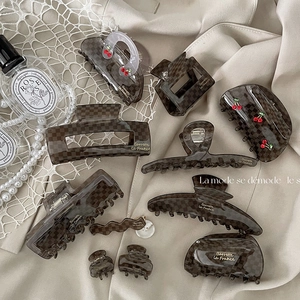 Detail view of acetate checkerboard hair clips with cherry charms on lace fabric