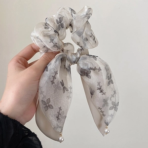 Detail of grey organza scrunchie with floral butterfly pattern and pearl ribbon drops