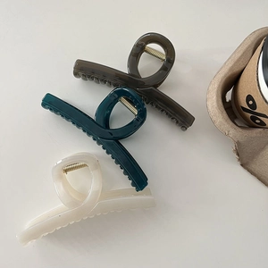 Close-up of three elegant hair claws in brown, green, and cream with glossy finish