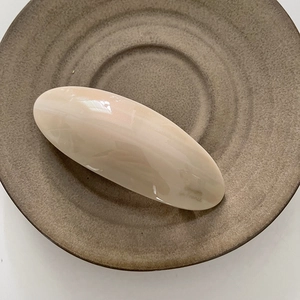 Gros plan sur la barrette ovale crème avec finition en résine brillante sur plat céramique