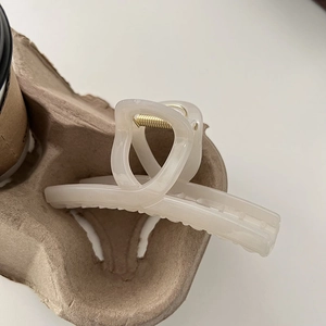 Close-up of cream marble hair claw clip with golden spring and crossover teeth detail