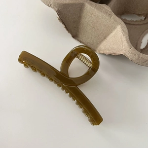 Detail of olive green translucent resin hair claw clip with golden metal spring