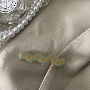 Detailed view of checkered acetate wavy hair claw clip on silk fabric with pearls