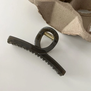 Detail of a large amber translucent shark hair claw clip with golden metal spring