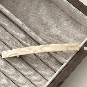 Detailed macro view of the cream marble resin hair barrette with gold metal spring clip