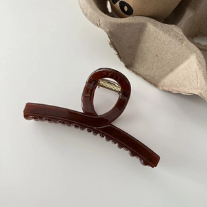 Detailed view of a dark amber resin hair claw clip with golden metal spring