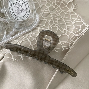 Detail of grey checkerboard acetate hair claw clip with golden Barrette La France text