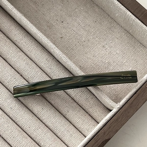 Detail of a dark green marble texture hair barrette clip with elegant gold lettering