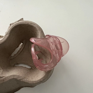 Close-up of pink translucent hair claw clip with large teeth design on a pulp tray