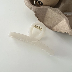 Detailed view of cream-white French hair claw clip with elegant minimalist cross design