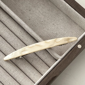 Close-up of cream marble resin barrette on linen display with silver spring metal clip