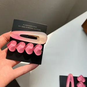 Detailliertes Set aus matten rosa Herz-Haarspangen auf schwarzer Displaykarte