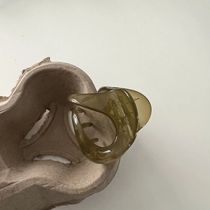 Detail view of translucent olive green shark hair claw clip on neutral background