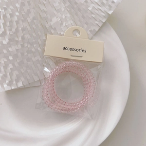 Transparent pink spiral hair ties in phone cord style with minimalist accessories tag