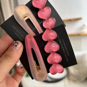 Detail von rosa Harz-Herz-Haarspange und mattem Tropfen-Haarnadel-Set mit Goldclips