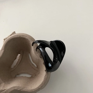 Glossy black hair claw clip with cutout design displayed on craft paper holder