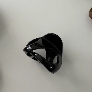 Macro shot of minimalist black glossy hair claw clip with a modern twisted streamlined design