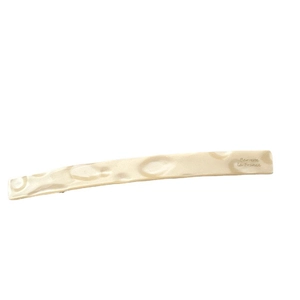 Minimalist pale gold barrette with hammered texture and French lettering on a white background