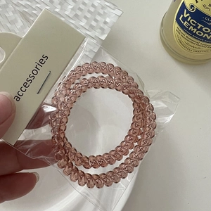 Detail view of two amber spiral hair ties in transparent packaging with card