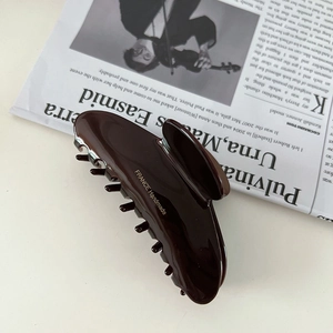 Detailed macro view of dark coffee resin hair claw clip with golden handmade lettering