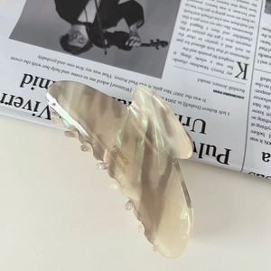 Detail view of large acetate shark hair clip with handmade France lettering and pearl texture
