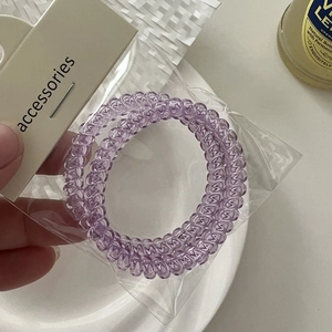 Close-up of two light purple spiral telephone wire hair ties on a gray display card