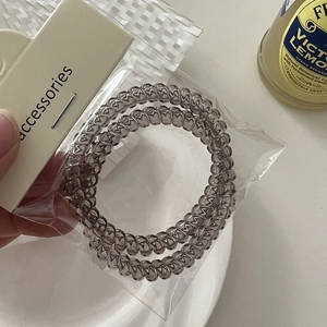 Close-up of translucent grey spiral hair ties in transparent packaging with card
