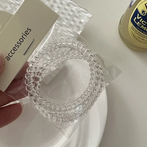 Three-piece set of transparent spiral phone cord hair ties in minimal retail packaging