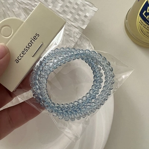 Detail view of light blue spiral telephone wire hair ties on a white accessory card