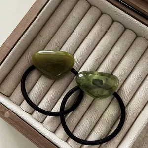 Detailed macro view of two-piece minimalist hair ties with polished green resin pendants